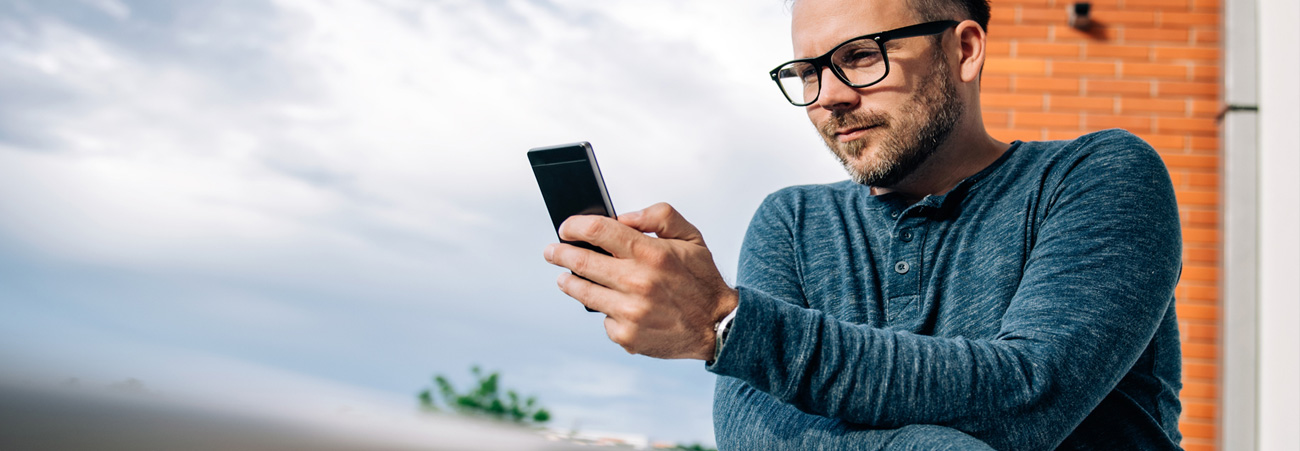 Mann blickt bei einem heraufziehenden Sturm auf sein Handy.