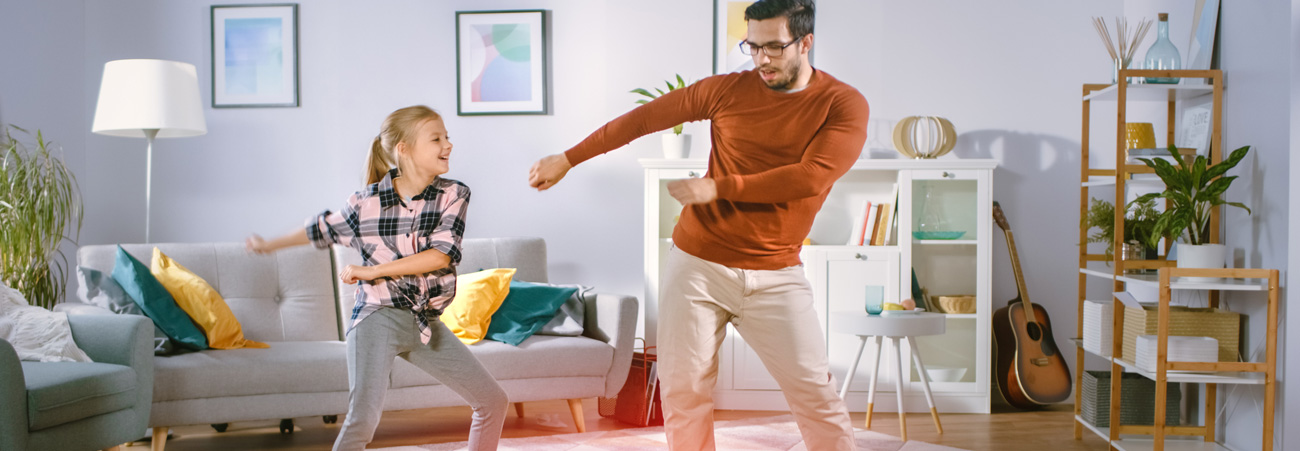 Tochter und Vater haben Spaß, während sie gemeinsam im Wohnzimmer tanzen