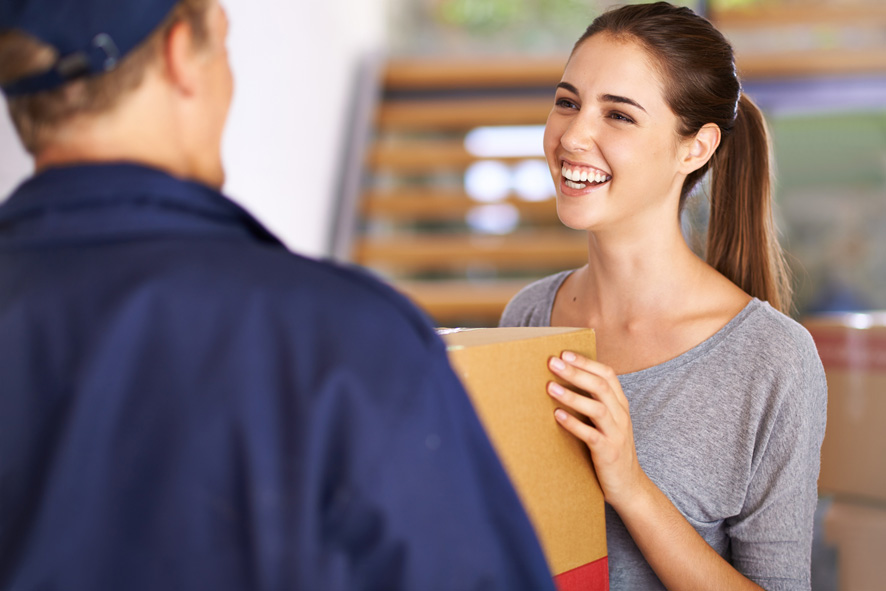 junge frau nimmt von postboten paket entgegen