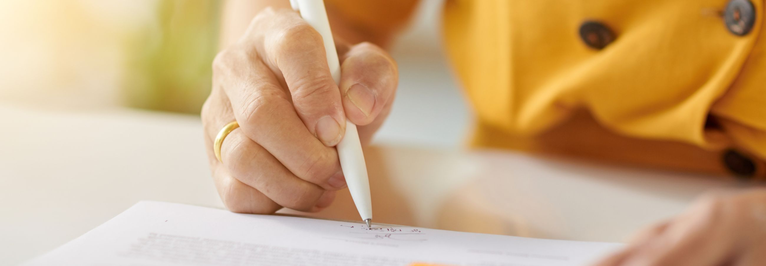 Eine Person füllt ein Formular mit einem Stift aus.