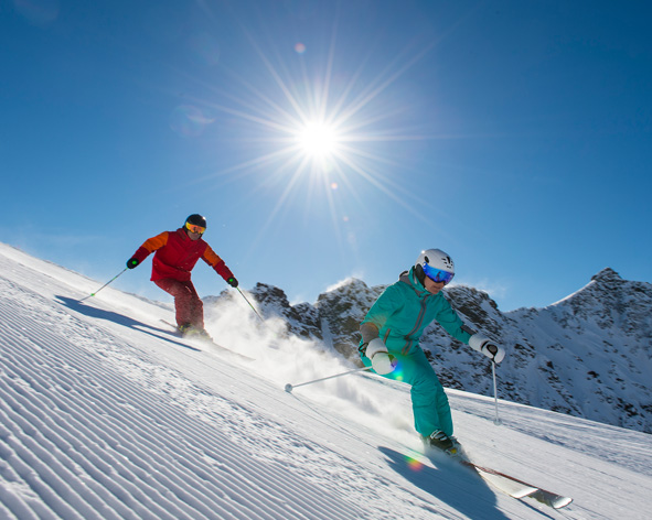 Zwei Skifahrer wedeln Piste runter