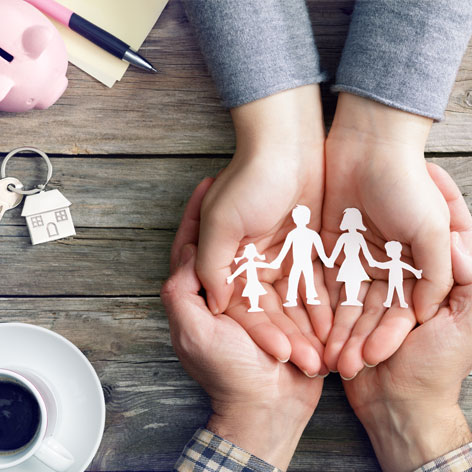 große und kleine Hände halten den Scherenschnitt einer Familie