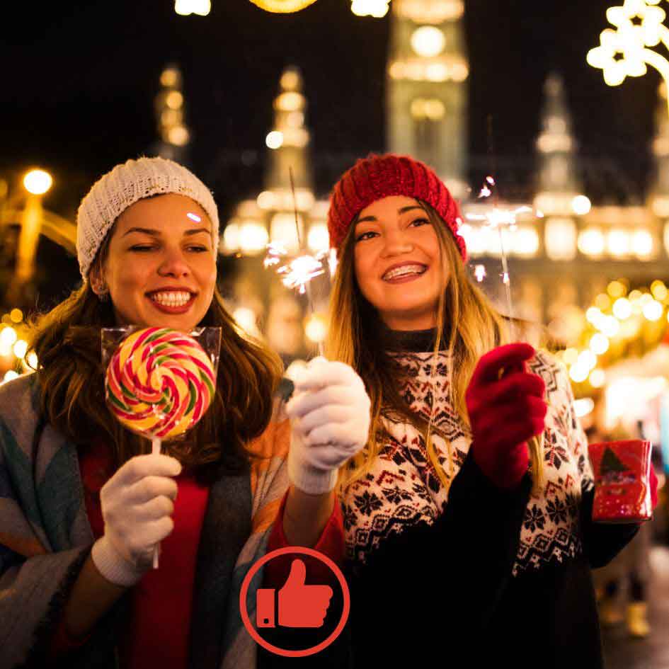 Zwei lachende junge Frauen auf dem Weihnachtsmarkt