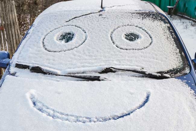 Schnee-Smiley auf Motorhaube Auto