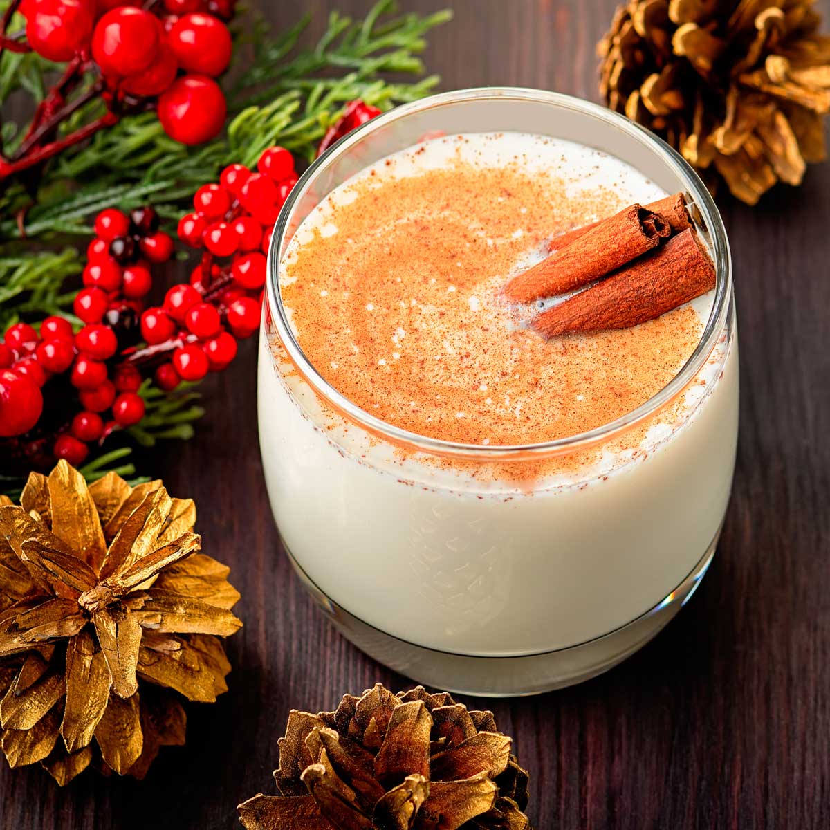 Ein mit Eggnog gefülltes Glas, dekoriert mit zwei Zimstangen.