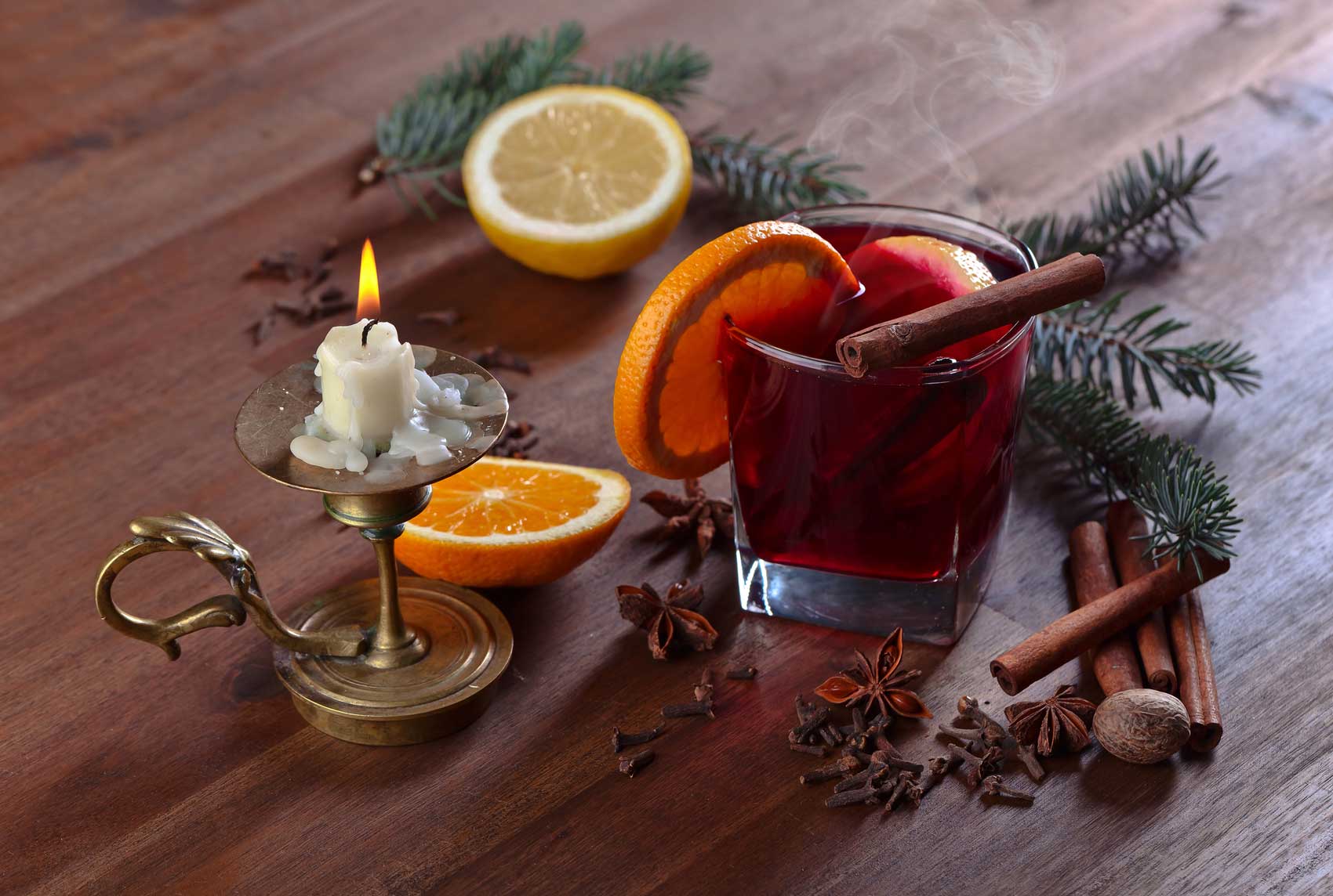 Ein Glas roter Glühwein mit Orangenscheiben und Zimststange.