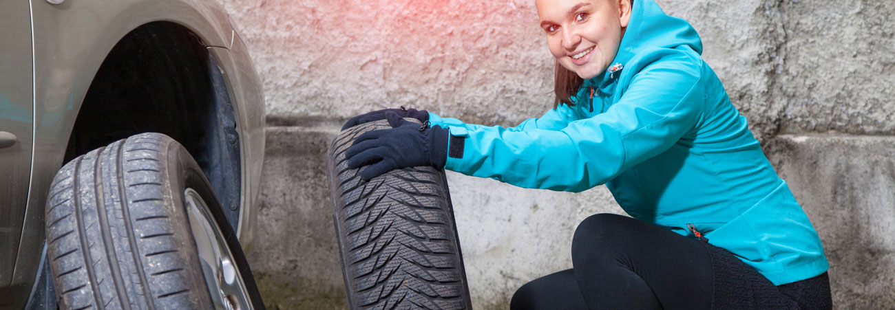 Junge Frau wechselt Reifen am Auto