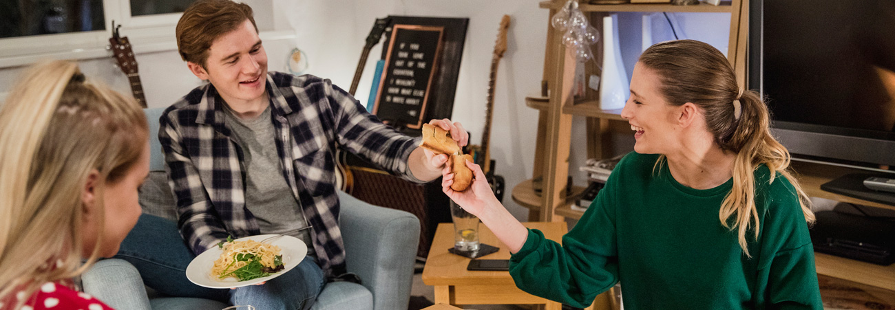 Junge Menschen in einer Wohngemeinschaft essen gemeinsam