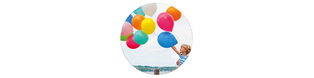 Eine Familie mit kleineren Kindern sitz auf einem Steg mit Luftballons in der Hand.