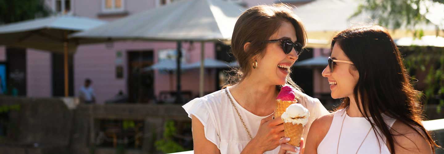 Zwei Frauen lachen und essen ein Eis. 