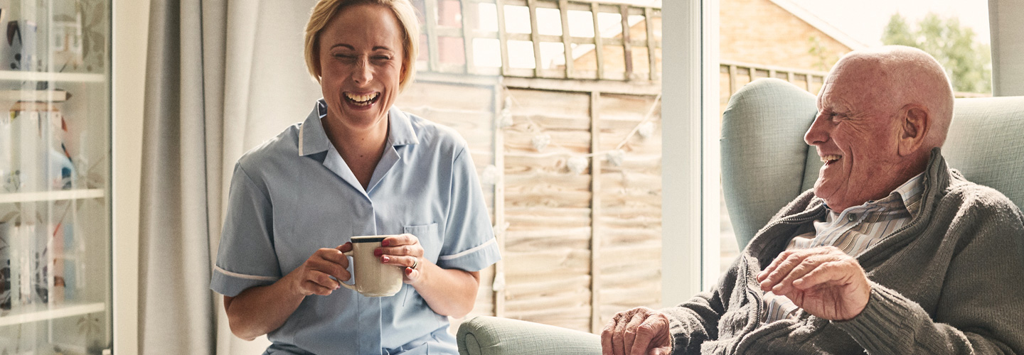 Pflegerin und ein Senior lachen gemeinsam