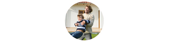 Vater und Sohn spielen im Garten vor ihrem Eigenheim