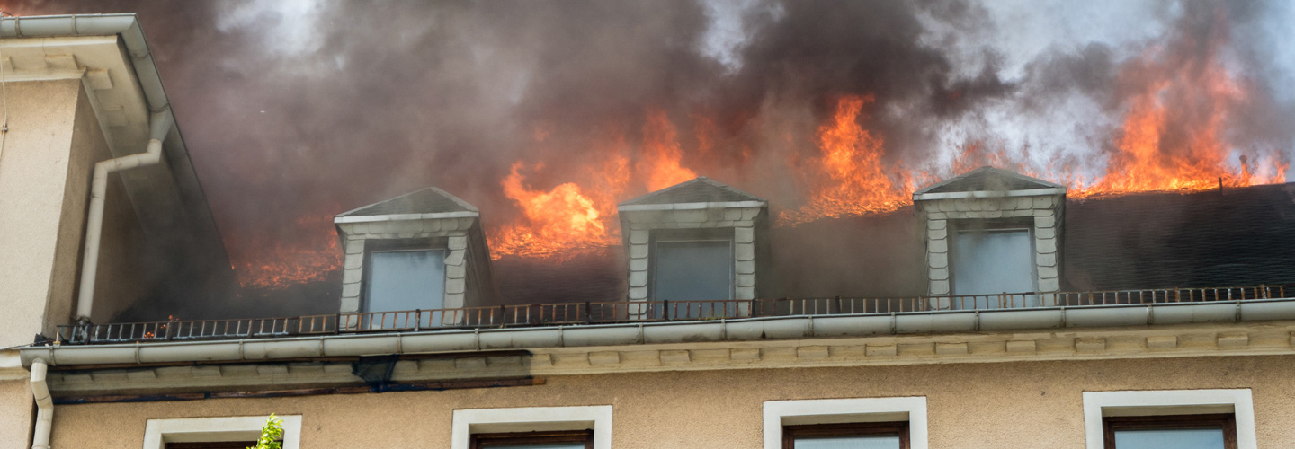 Aus den Fenstern eines Mehrfamilienhauses schlagen Flammen