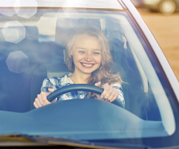 Junge Frau fährt lächelnd Auto