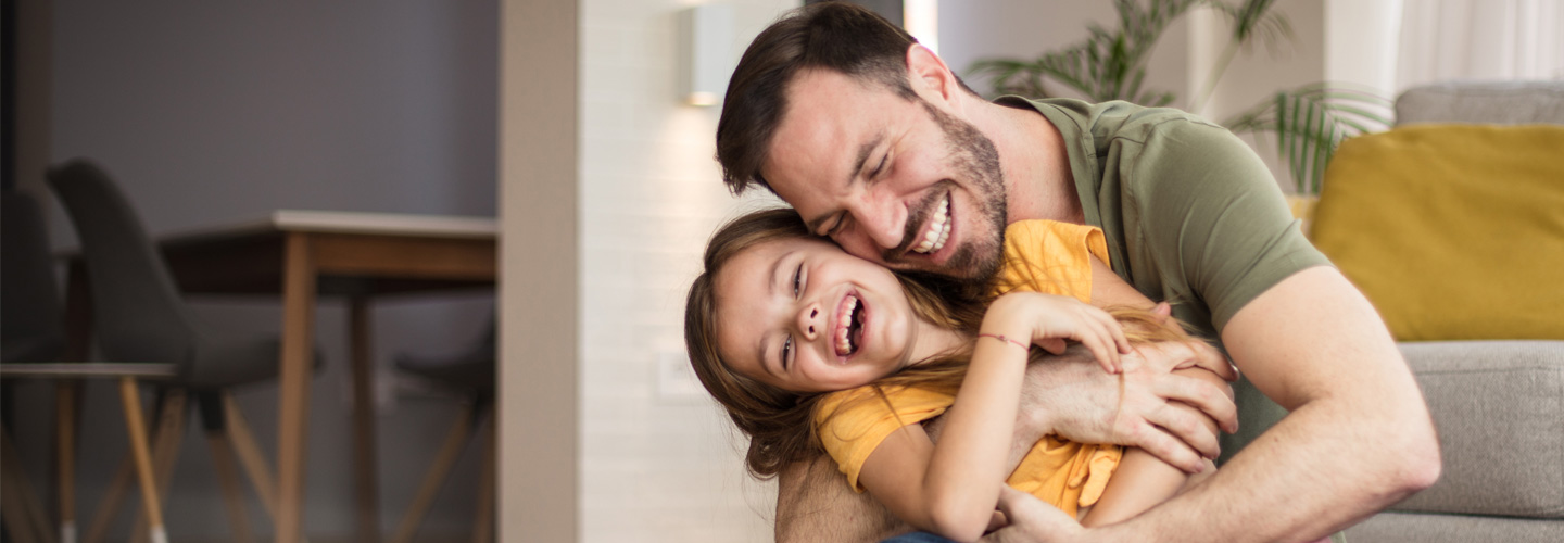 Vater und Tochter umarmen sich und lachen. 