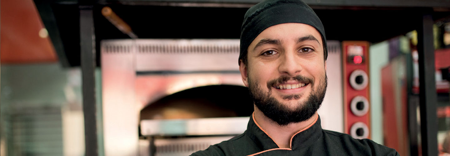 Ein Mann in Arbeitskleidung steht vor einem Backofen.